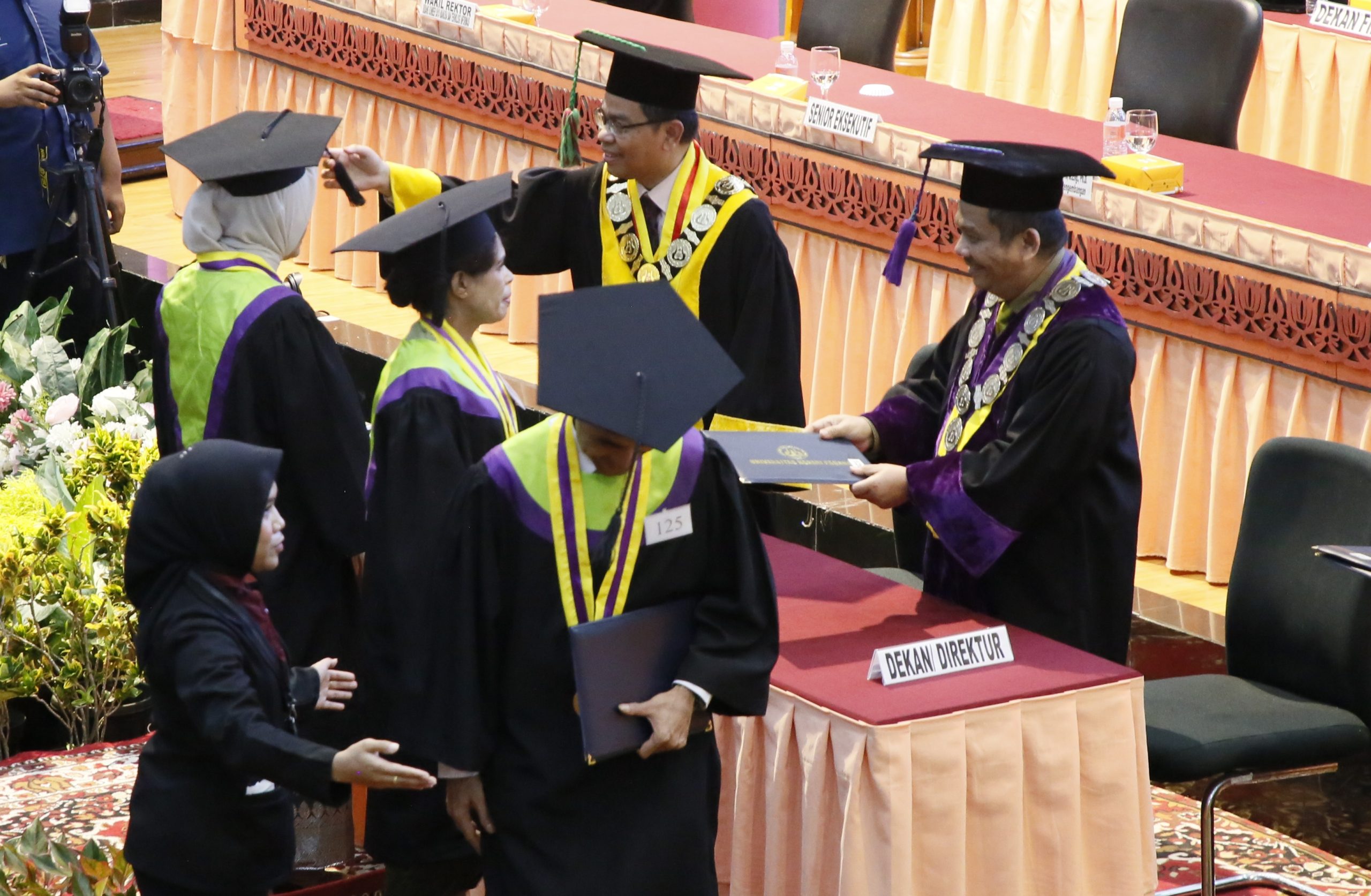 Rektor UNP Ir. Krismadinata, Ph.D saat memindahkan jambul wisudawan dan Dekan Fakultas Bahasa dan Seni Prof. Ermanto memberikan ijazah wisudawan, Selasa (30/6/2026). (Foto: Huswantun Hasanah/ Kantor Komunikasi dan Pemasaran Strategis)