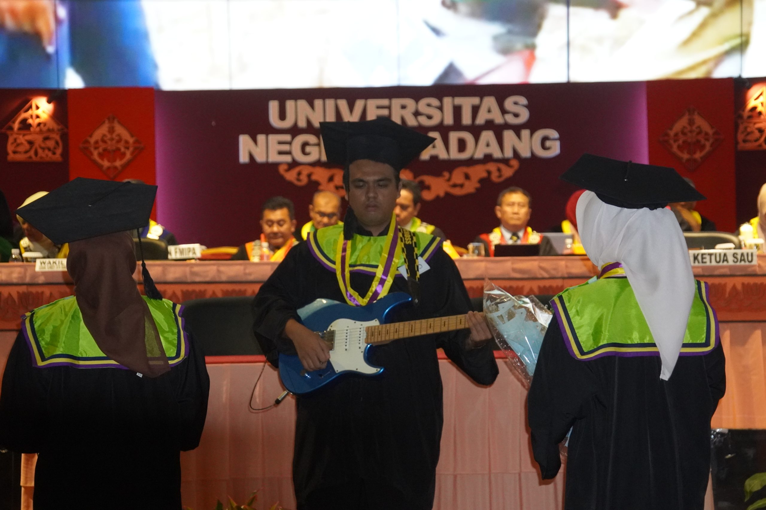 Rafi (tengah) saat tambil bermain gitar pada Wisuda UNP 143, Rabu (1/7/2026). (Foto: Dian Melsa/ Kantor Komunikasi dan Pemasaran Strategis)